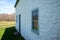 Side view of white colonial American stone cottage in rural landscape