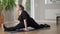 Side view wide shot of charming obese young woman sitting in twine pose on exercise mat doing breathing exercise and