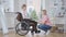 Side view wide shot of young paralyzed disabled woman on wheelchair talking with supportive friend at home. Upset