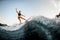 Side view of woman balanced on surf style wakeboard on splashed river wave