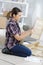 Side view woman knelt on floor assembling furniture