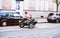 Side view of woman in pink coat driving a green motorcycle with sidecar