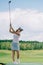 side view of woman in polo sunglasses and cap playing golf