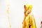 side view of woman in raincoat painted with yellow and red paints standing in hood