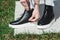 Side View Of Woman`s Black Leather Ankle Boots. Outdoor Shot Over White Stone in park