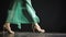 Side view of woman slender legs in high heel shoes and a long dress, walking in a dark studio. Close up of female legs