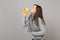 Side view of woman in sweater, scarf blowing sending air kiss to lemon, orange isolated on grey background. Healthy