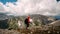 Side view of woman walking tourist conquered and climbed peak in orange jacket and backpack, stopping and looking with