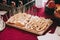 Side view of a wooden board with sliced pieces of different types of cheese on skewers. Catering