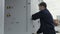 Side view of a worker opens the door of a metal cabin for the mechanic equipment storage and taking a wire. Scene