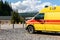 Side view of yellow ambulance rescue ems van car parked near countryside rural road at highland mountain resort area