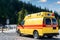 Side view of yellow ambulance rescue ems van car parked near countryside rural road at highland mountain resort area