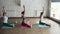 Side view of yoga students doing stretching exercises developing flexibility. Three women are sitting on colorful mats