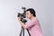 Side view of young asian photographer holding digital camera, while working in studio