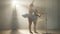 Side view of young ballet teacher and little student moving hands in slow motion standing at ballet barre in backlit fog