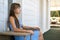 Side view of young beautiful woman resting on fresh air sitting on porch at home. Concept of enjoying nature with good weather