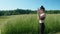 Side view of young brunnette in a green field talking on phone.