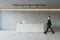 Side view of young businessman walking in modern concrete office reception interior with desk. Lobby concept. Worker and CEO