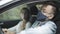 Side view of young caucasian man in covid face mask and eyeglasses sitting on driver`s seat and talking with woman at