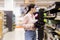 Side view of young Caucasian woman wearing glasses holds baking dish for cupcakes. Shopping and choice of kitchen tools