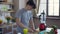Side view of young concentrated Asian man chopping banana with knife on countertop in kitchen. Portrait of relaxed happy