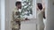 Side view of young interracial couple arguing shouting and gesturing indoors. Stressed African American military man and