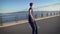 Side view of young man riding skateboard alone on waterfront with view of sea.