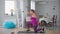 Side view of young obese Caucasian woman exercising at home indoors. Wide shot of motivated inspired overweight lady