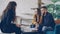 Side view of young people real estate agent and buyers looking at house plan sitting at table in modern loft style house