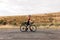 Side view of young professional cyclist walking with her road bike on countryside