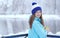 Side view of young smiling woman with a cup of hot tea or coffee on snowy winter waterside.