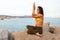 Side view of young woman doing yoga on a rock by the sea. Female practicing gomukhasana with eagle arms. Copy space.