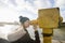 Side view of young woman in hooded sweatshirt looking through telescope by river Thames, London, UK