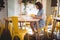 Side view of young woman sitting tablet and papers at coffee shop