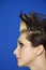 Side view of young woman with spiked hair over colored background