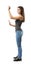 Side view of young woman in top and jeans standing, one arm with open palm at belly level, other before face in pinch