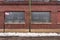 Side of vintage red brick industrial building with snow on street and frosted windows