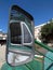 Side windows of an old green rusty vintage bus reflected in the rear view mirror parked in a square in a village in cyprus