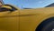 Side of a yellow sport car against background of building and sky