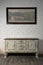Sideboard and hanged painting over wooden floor and bricks wall