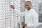 Sideview of smiling man is choosing eyeglasses in optical shop.