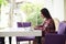 Sideview of young dark-haired woman with laptop in bright room