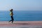 Sideview of young woman running by seaside