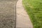 Sidewalk with green fescue on one side and brownish bermuda grass on the other side in the springtime