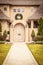 Sidewalk leading to Arched door to upscale modern stucco home with Christmas wreath and electric icicles