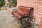 Sidewalk scene with wooden bench and brick wall.