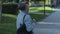 A sidewalk traveler elderly woman steps the urban streets outside. Pensioner tourist with backpack behind turning around