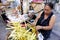 Sidewalk vendor sells Suman or steamed glutenous rice in palm tree leaves and other Filipino delicacies in her makeshift stall