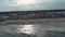 sideways aerial footage of a gorgeous summer landscape at Kure Beach with people relaxing on the beach and fishing on Kure Pier