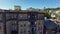 sideways aerial footage of a red brick apartment buildings with restaurants, retail stores, tall lush green palm trees, billboards